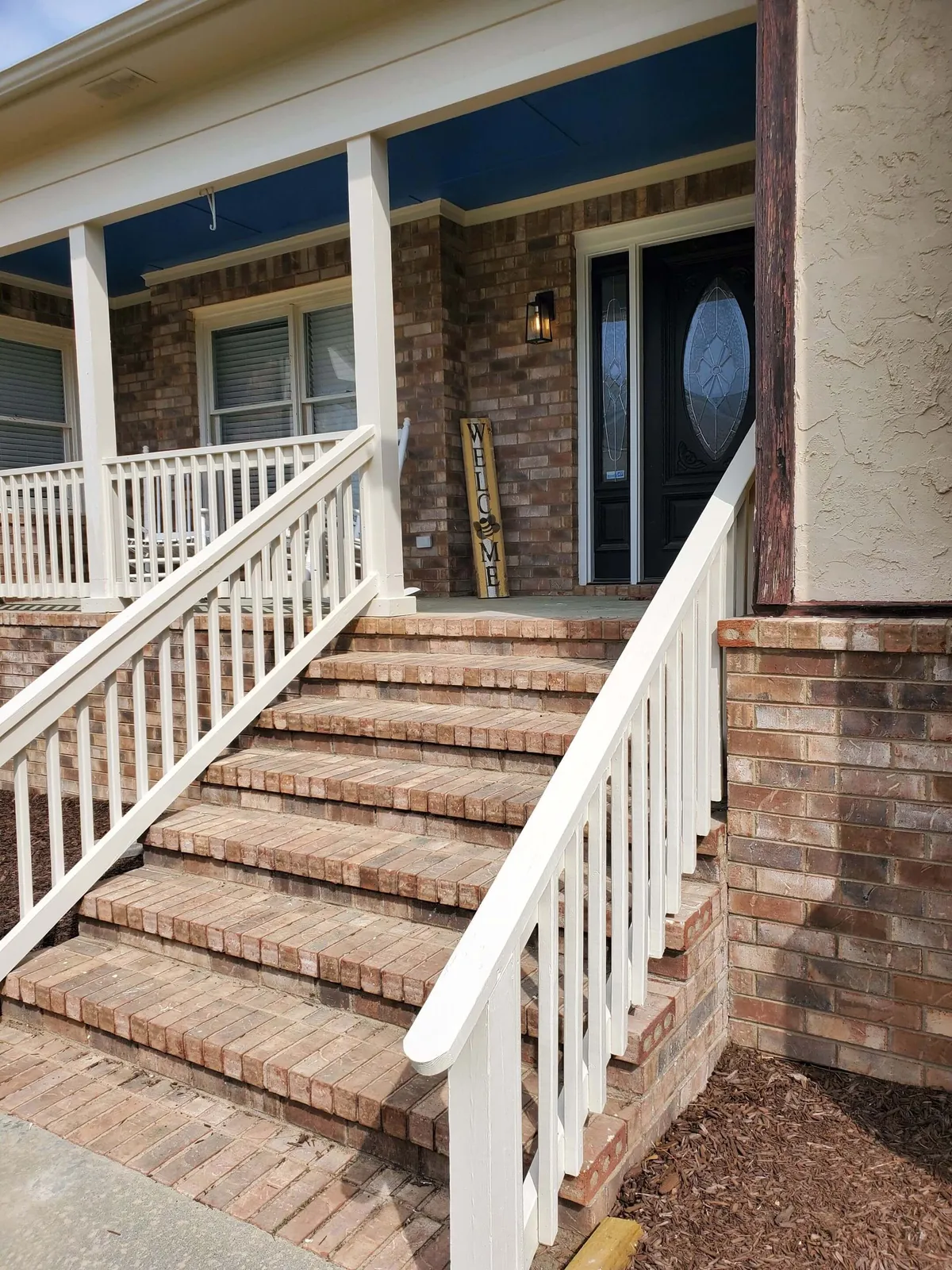 The exterior of the 'BEA Hive,' highlighting inviting front steps, a welcoming sign, and the entrance door, with an atmosphere suggesting guests gathering and mingling on the porch.