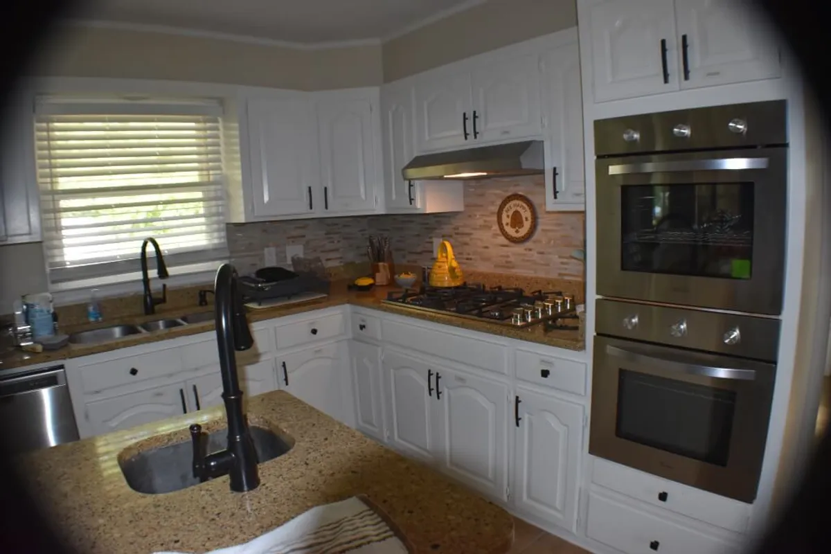A cozy and functional kitchen featuring a granite countertop, stainless steel appliances, a central kitchen sink, and inviting wooden accents. The space feels warm and bustling, perfect for meal preparation, cooking family recipes, or casual socializing.