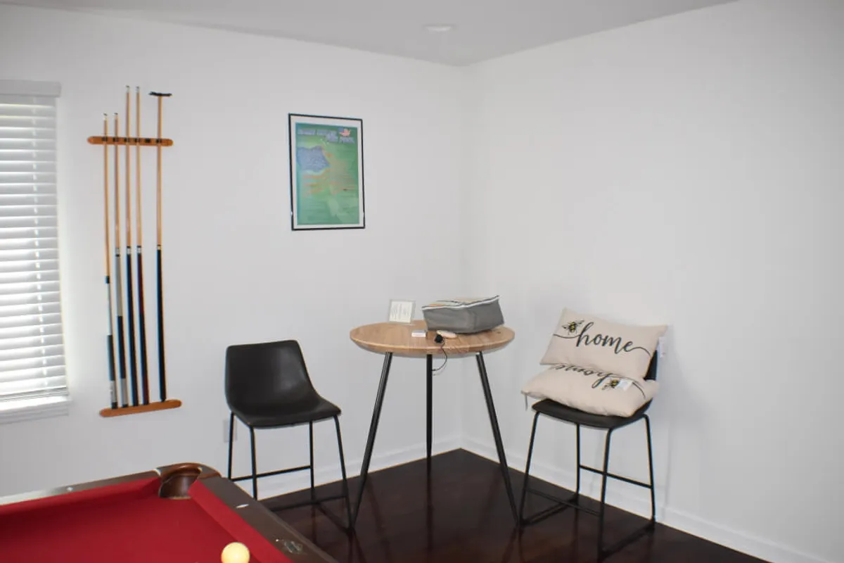 An inviting game room featuring a billiard table, pool cues, and a casual sitting area, all set for lively games, conversations, and friendly competition.
