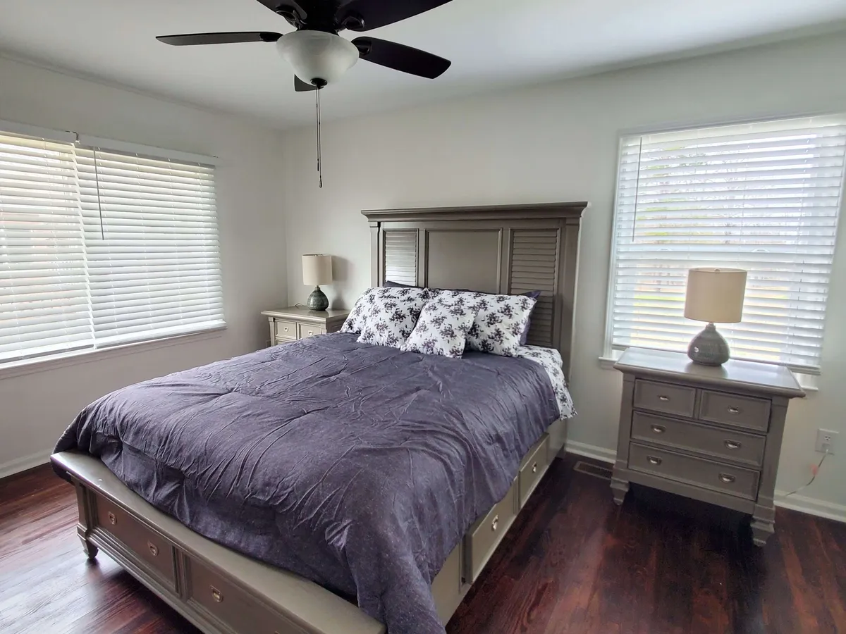 A serene bedroom featuring a comfortable bed with crisp linens, nightstands on both sides, and large windows that allow soft natural light to flow into the room. The space is uncluttered, with gentle hues and minimal decor, evoking peace and tranquility.