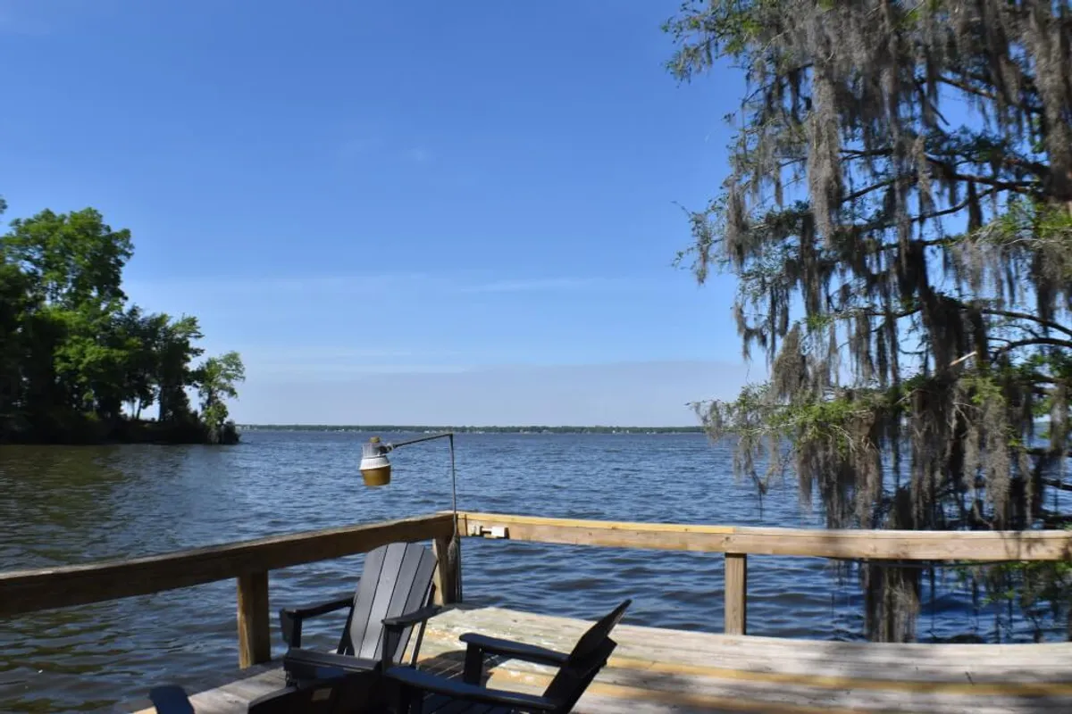 A wooden deck overlooking the lake, outfitted with a hammock and surrounded by moss-covered trees. The deck offers a serene spot for relaxing, reading, or enjoying meals with a stunning water view.